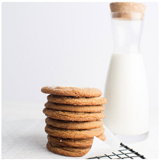 A glass of milk next to a stack of Snickerdoodle cookies, representing the final product of a cookie dough fundraiser